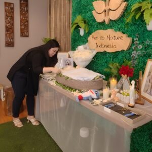 Staf merapikan jenazah hewan peliharaan di meja perpisahan dengan dekorasi bunga dan lilin di Pet to Nature Indonesia.